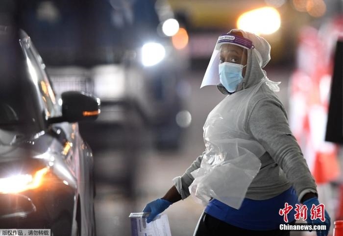 當(dāng)?shù)貢r(shí)間12月18日，英國政府公布的數(shù)據(jù)顯示，當(dāng)天英國新增奧密克戎毒株感染病例10059例。鑒于奧密克戎毒株感染病例激增，住院人數(shù)不斷上升，倫敦市長(zhǎng)宣布倫敦進(jìn)入“重大事故”狀態(tài)。圖為倫敦的一個(gè)免下車檢測(cè)中心，一名醫(yī)務(wù)工作者正準(zhǔn)備對(duì)司機(jī)進(jìn)行核酸檢測(cè)。