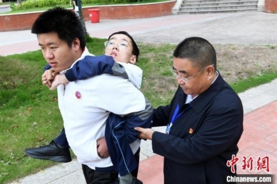 朱金祥背著鐘華強去教室上課的路上，也經(jīng)常碰到值班的校領(lǐng)導(dǎo)和老師前來搭把手。 卓忠偉 攝