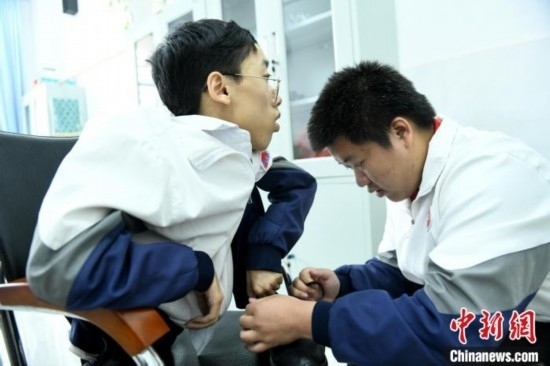 江西省南康中學(xué)北校區(qū)的高三學(xué)生朱金祥(右)正在給鐘華強(左)系好鞋帶。 卓忠偉 攝