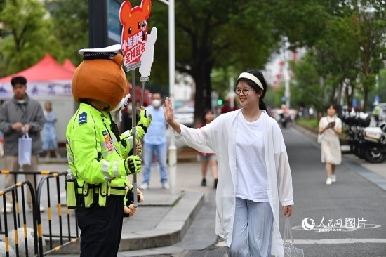 6月7日上午9時(shí)，隨著鈴聲的響起，2023年江西高考正式開(kāi)考，江西省的53.57萬(wàn)考生以縣（區(qū)）為單位隨機(jī)安排在全省256個(gè)考點(diǎn)、18968個(gè)考場(chǎng)參加高考。圖為“小熊交警”和考生擊掌鼓勵(lì)。 人民網(wǎng)記者 時(shí)雨攝