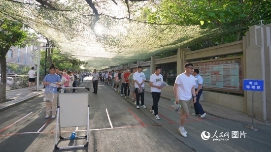 6月7日，烏魯木齊市第七十中學(xué)門(mén)口，考生們有序進(jìn)入考場(chǎng)。人民網(wǎng) 李欣洋攝