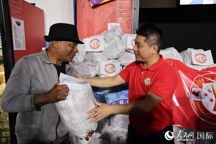 巴西中國(guó)浙江商會(huì)會(huì)長(zhǎng)鄭俠茂向社區(qū)居民轉(zhuǎn)交捐贈(zèng)物資。人民網(wǎng)記者 時(shí)元皓攝