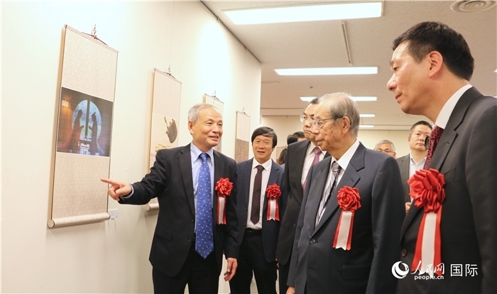 “湖州印象”攝影展主創(chuàng)、世界華人攝影協(xié)會副會長馮學敏向吳江浩大使、福田康夫前首相等嘉賓介紹展出作品。（人民網(wǎng) 許可攝）