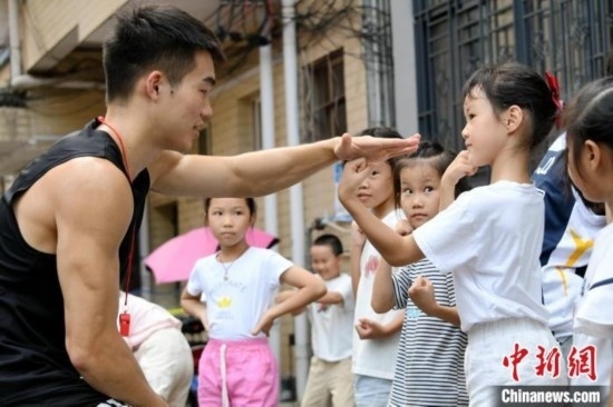 圖為大學生志愿者在組織孩子們參加體育健身活動。廖光福 攝