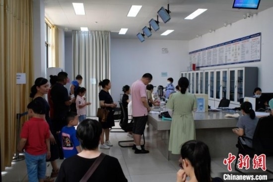 圖為在戶籍辦證廳內(nèi)排隊(duì)等待的家長(zhǎng)和孩子。劉俊聰 攝