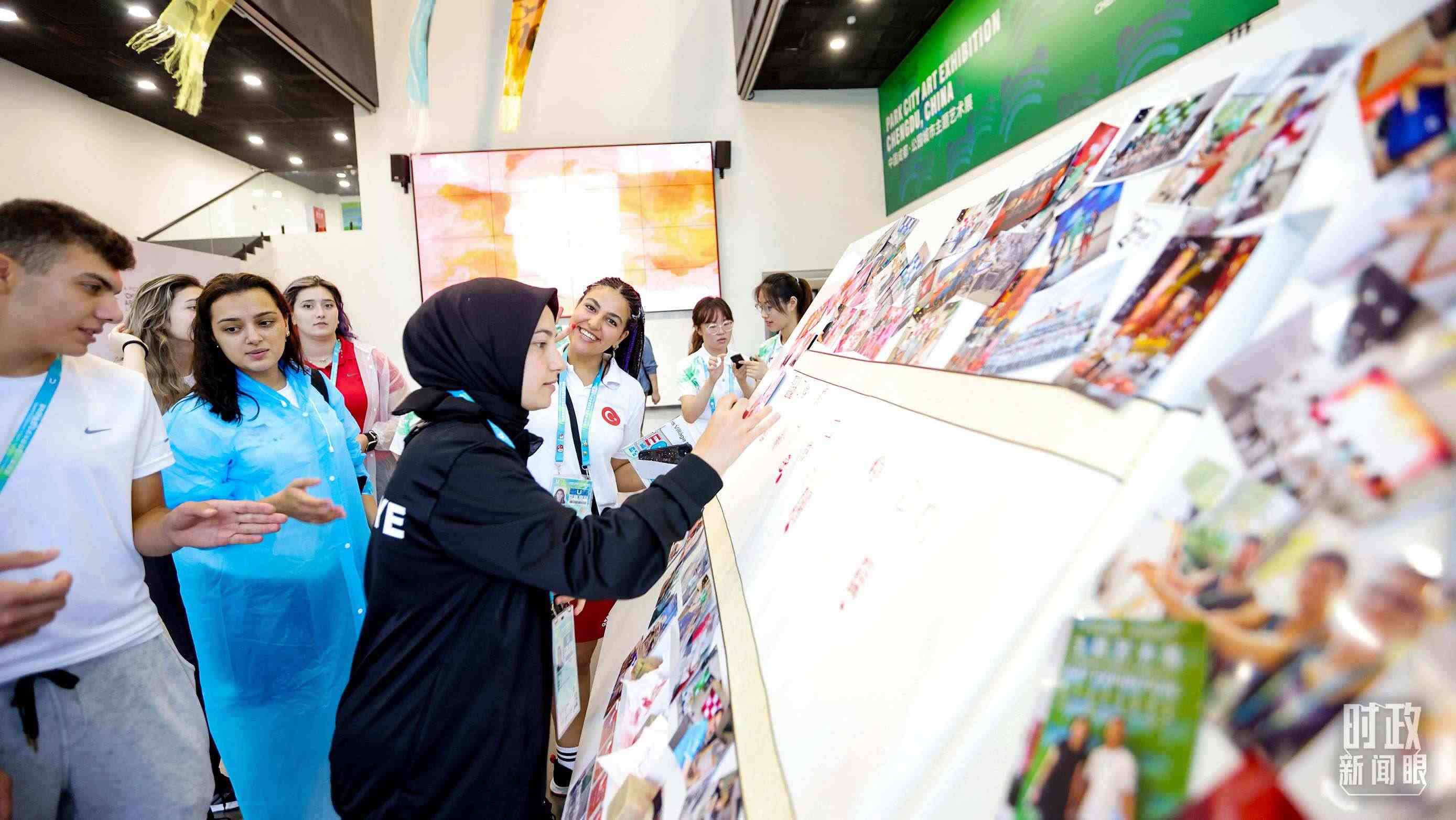 各國(guó)青年運(yùn)動(dòng)員正在參觀成都大運(yùn)村內(nèi)的“雪山下的公園城市，煙火里的幸福成都”主題藝術(shù)展。（總臺(tái)央視記者魏幫軍拍攝）