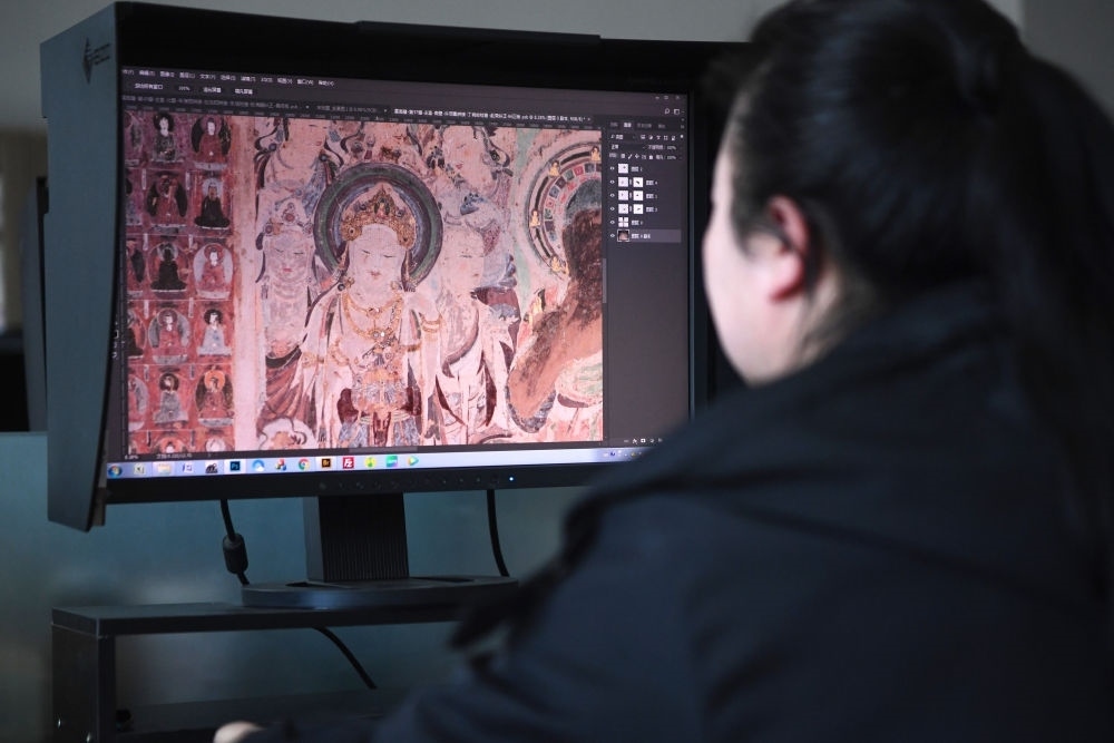 敦煌研究院文物數(shù)字化保護(hù)團(tuán)隊(duì)圖像處理人員年海麗在拼接壁畫圖像（2023年4月25日攝）。數(shù)字化探索為莫高窟的保護(hù)與傳承開辟了全新路徑，數(shù)字技術(shù)讓敦煌文物走出洞窟，跨出國門，走向“永久保存、永續(xù)利用”。新華社記者 陳斌 攝
