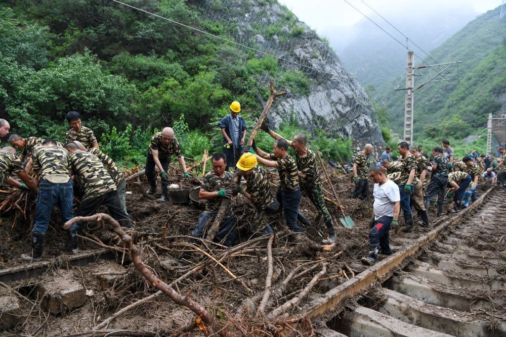 8月1日，在北京市門(mén)頭溝區(qū)水峪嘴村附近一段被阻斷的鐵路線上，中鐵六局工作人員在清理軌道上的雜物，全力恢復(fù)交通。新華社記者 鞠煥宗 攝