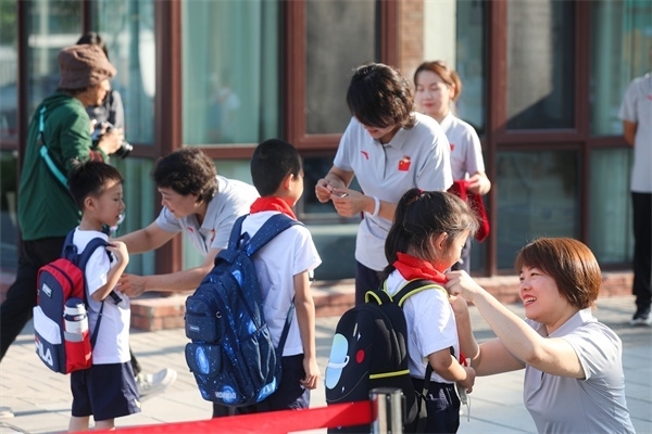 8月30日，雄安史家胡同小學學生體驗學校生活。老師為學生佩戴?；?。