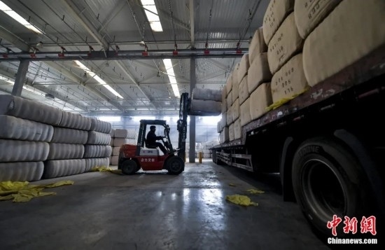 新疆喀什綜合保稅區(qū)，喀什啟路國(guó)際貿(mào)易有限公司的倉(cāng)庫(kù)內(nèi)，工人正在裝載從塔吉克斯坦和烏茲別克斯坦進(jìn)口的棉花。劉新攝