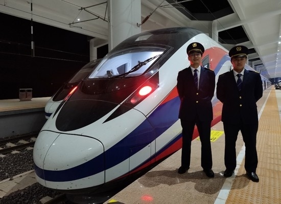 劉銀能（右一）與中國師父鄔俊鴻在動車組前合影。受訪者供圖