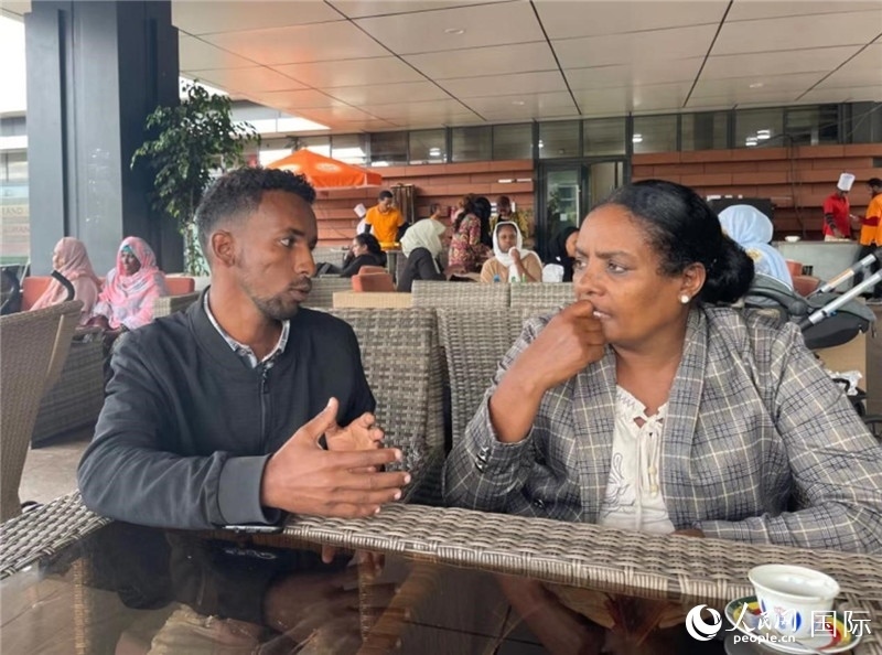 約漢斯（圖左）與德貝拉在友誼廣場咖啡廳交談。人民網(wǎng)記者 趙艷紅攝