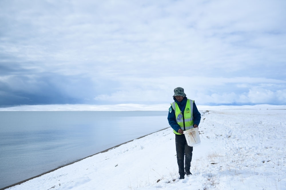 2021年10月20日，在青海省果洛藏族自治州瑪多縣扎陵湖鄉(xiāng)勒那村，三江源國家公園黃河源園區(qū)生態(tài)管護員在扎陵湖邊撿拾垃圾。新華社記者 張龍 攝