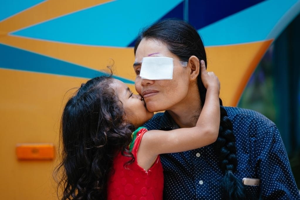 2019年3月15日，在柬埔寨磅湛省醫(yī)院，即將接受白內(nèi)障手術(shù)的患者孫美樂接受女兒的親吻祝福。在接受了中國醫(yī)療隊的白內(nèi)障義診手術(shù)后，她的視力逐步恢復(fù)，生活有了新的光明和希望。