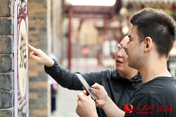 選手安德烈（俄羅斯）在老師指導(dǎo)下學(xué)習(xí)墻壁上張貼的生僻字。人民網(wǎng) 盧鵬宇攝