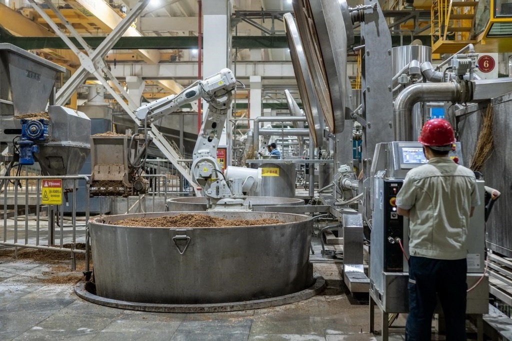 907車間里，機械臂正在撒料裝甑。嚴磊攝