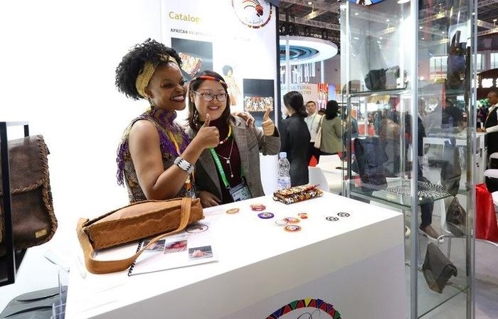 11月6日，一位參觀者（右）在第六屆進博會國家展南非展臺試戴傳統(tǒng)首飾。