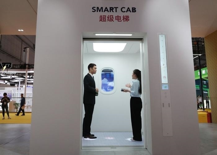 11月5日，工作人員（右）在第六屆進博會上向參觀者介紹奧的斯公司全新推出的超級電梯。