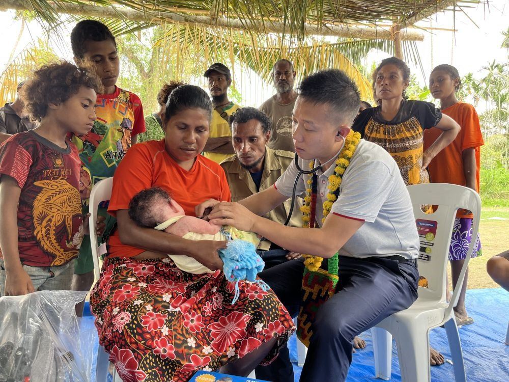 2023年8月5日，在巴布亞新幾內(nèi)亞中央省的一個(gè)村莊里，第12批援巴新中國(guó)醫(yī)療隊(duì)副隊(duì)長(zhǎng)、新生兒科副主任醫(yī)師劉振球?yàn)閶雰禾仿犜\檢查。泰樂出生時(shí)患有重癥，一度生命垂危，經(jīng)過劉振球與當(dāng)?shù)蒯t(yī)護(hù)人員的救治最終痊愈。從2002年起，中國(guó)連續(xù)向巴新派出12批醫(yī)療隊(duì)，為提高巴新醫(yī)療衛(wèi)生水平作出積極貢獻(xiàn)。
