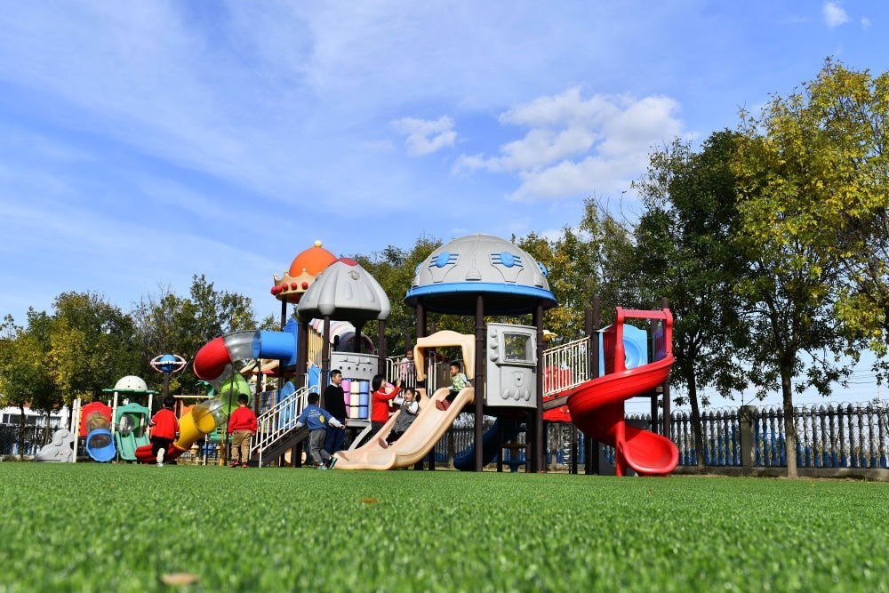 在山東省東營市墾利區(qū)楊廟社區(qū)幼兒園，孩子們在老師的帶領(lǐng)下進行戶外活動（2021年10月19日攝）。新華社記者 郭緒雷 攝