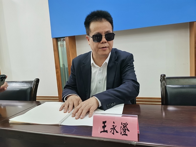 全國人大代表王永澄正在閱讀盲文版代表建議答復(fù)。本報記者 張 璁攝