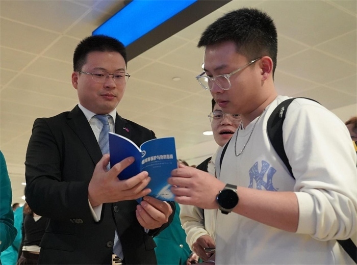 工作人員（左一）在發(fā)放《中國領(lǐng)事保護與協(xié)助指南》。 中國駐迪拜總領(lǐng)事館供圖