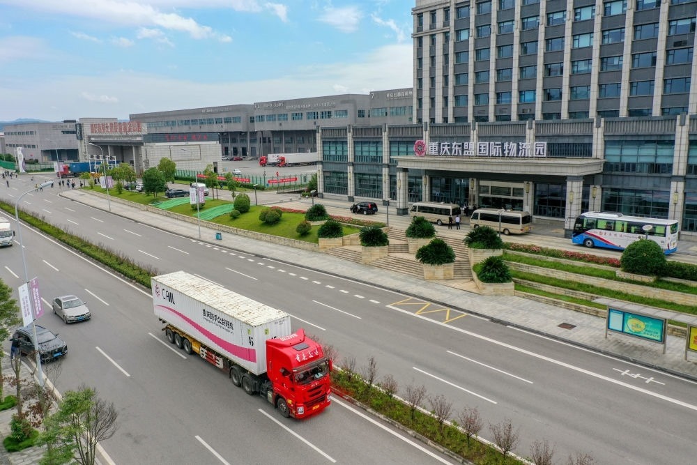 2023年10月11日，滿載筆記本電腦配件、發(fā)電機(jī)組件等產(chǎn)品的西部陸海新通道跨境公路班車從重慶南彭公路保稅物流中心駛出，將途經(jīng)廣西憑祥，直達(dá)越南（無人機(jī)照片）。新華社記者 黃偉 攝