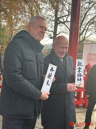柏林市長韋格納（右）、動物園監(jiān)事會主席布魯克曼（左）手持中國文化中心工作人員現(xiàn)場手書的中文名字。人民網(wǎng)記者 徐馨攝