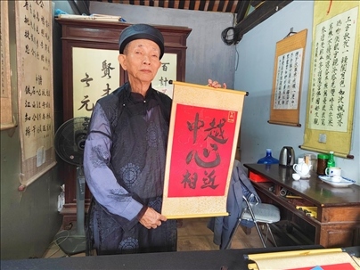 越南首都河內(nèi)文廟內(nèi)，阮明珠展示“中越心相近”書法作品。