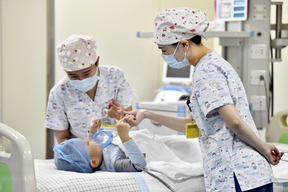 在山東省棗莊市婦幼保健院兒童ICU病房，醫(yī)護(hù)人員為完成靶向治療藥物諾西那生鈉的4歲脊髓性肌萎縮癥患兒加油鼓勁（2022年1月1日攝）。諾西那生鈉注射液是我國首個獲批治療脊髓性肌萎縮癥的進(jìn)口藥物，2019年進(jìn)入中國市場時，每針價格近70萬元。在2021年國家醫(yī)保目錄藥品談判中，以3.3萬元每針的價格進(jìn)入新版醫(yī)保藥品目錄。新華社記者 郭緒雷 攝