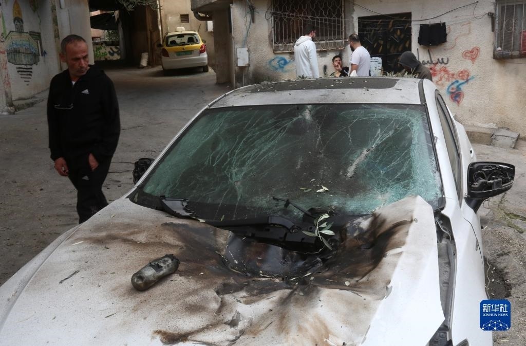 12月17日，在約旦河西岸城市圖勒凱爾姆附近的一處難民營(yíng)，人們查看在沖突中損毀的車輛。新華社發(fā)（尼達(dá)爾·艾仕塔耶?dāng)z）