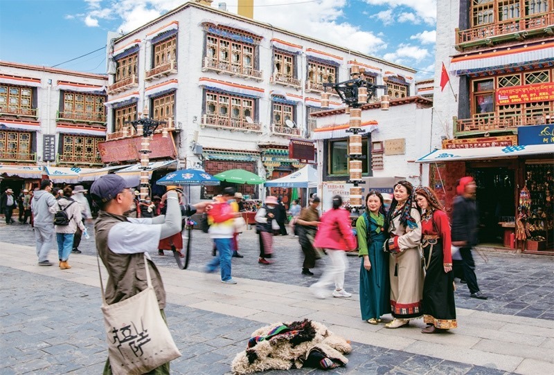 千年八廓街，見證民族團(tuán)結(jié)。2021年7月，習(xí)近平總書記來(lái)到位于西藏拉薩老城區(qū)的八廓街，感慨地說(shuō)：“千年八廓街，是我們各民族建起來(lái)的八廓街。各民族文化在這里交流交往交融，我們中華民族的大家庭在這里其樂融融?！眻D為2023年6月13日，游客身著藏裝在八廓街拍照留念。 新華社記者 姜帆/攝