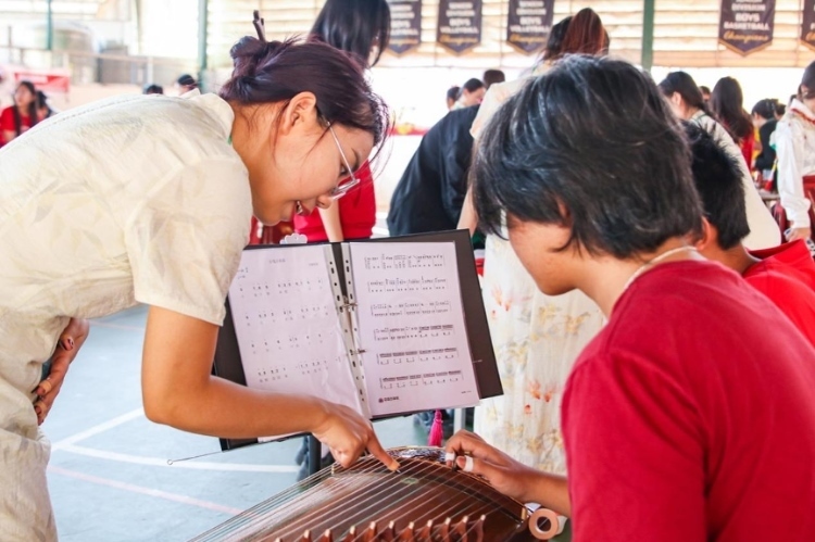 志愿者教師指導(dǎo)學(xué)生彈奏古箏?；顒又鬓k方供圖