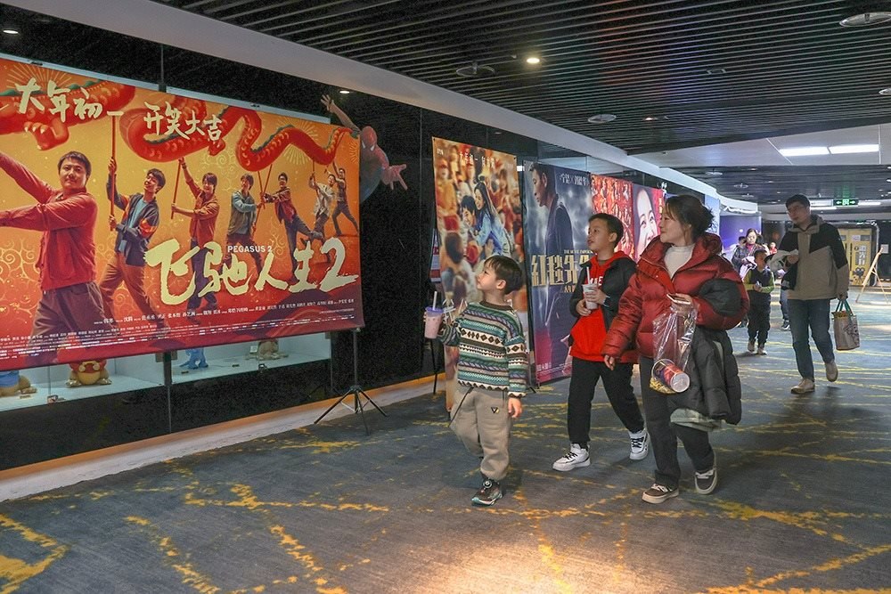 △ 2024年2月16日，在江西贛州一家電影院，觀眾從春節(jié)檔電影的宣傳展板前走過。