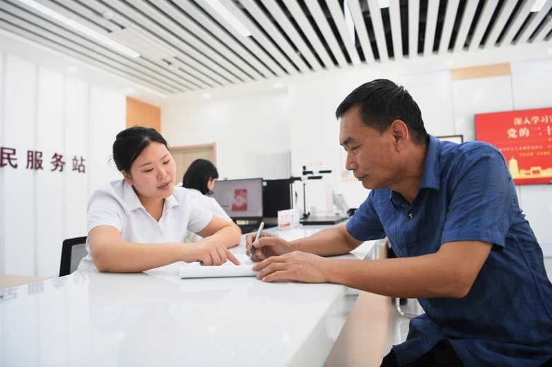 2023年5月23日，河北雄安新區(qū)容東片區(qū)南文營社區(qū)居民（右）在社區(qū)便民服務(wù)站辦理業(yè)務(wù)。