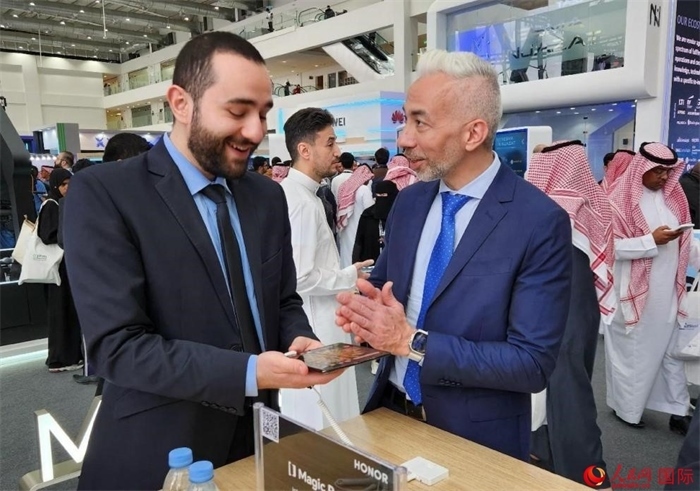 兩名觀眾在榮耀手機(jī)展臺(tái)前交流。人民網(wǎng)記者 管克江攝