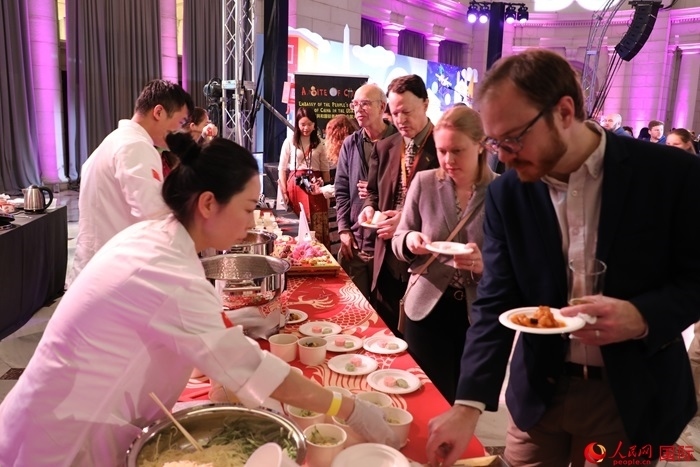 當(dāng)?shù)貢r(shí)間3月7日晚，華盛頓聯(lián)合車站廣場(chǎng)舉行駐美使團(tuán)“使館主廚挑戰(zhàn)賽”。圖為當(dāng)?shù)孛癖娫谥袊?guó)展臺(tái)前體驗(yàn)中國(guó)美食。人民網(wǎng)記者 李志偉攝