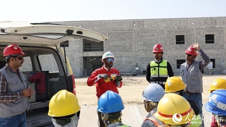 穆薩瓦爾(圖中紅衣人）現(xiàn)場演示工具操作規(guī)范。人民網(wǎng)記者 管克江攝