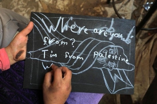 2023年12月28日，一名學(xué)生在加沙地帶南部城市拉法一所學(xué)校的臨時(shí)教室中寫(xiě)下“我來(lái)自巴勒斯坦”的字樣。新華社發(fā)（里澤克·阿卜杜勒賈瓦德攝）