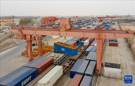 4月21日，二連浩特鐵路口岸龍門吊吊裝中歐班列集裝箱（無人機照片）。 新華社發(fā)（張海峰攝）