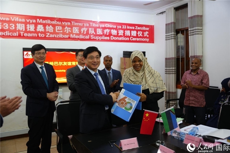 江蘇省蘇北人民醫(yī)院黨委書記束余聲與桑衛(wèi)生部首席秘書哈比巴交換捐贈書。中國援桑醫(yī)療隊(duì)供圖