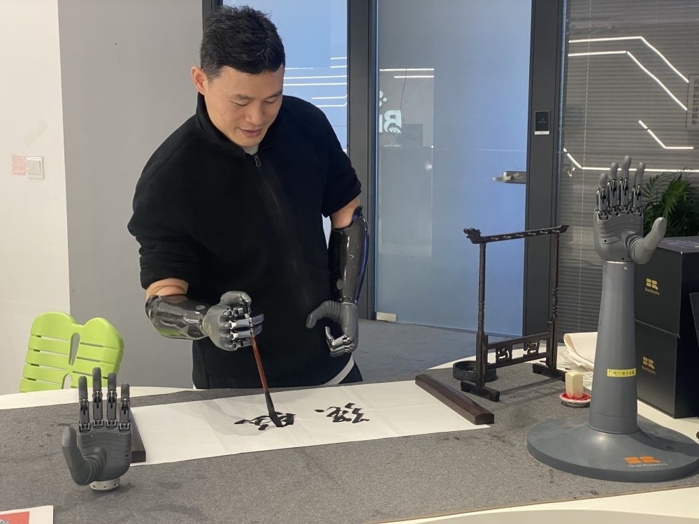 2024年3月29日，在浙江強腦科技有限公司展廳內，失去雙手的產品體驗官倪敏成依靠智能仿生手寫毛筆字。新華社記者 魏一駿 攝