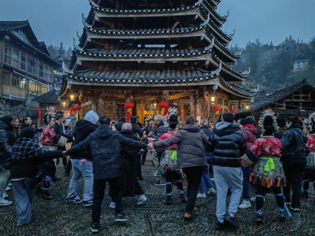 法國青年與當?shù)卮迕駹渴痔?。新華社記者 羅羽 攝