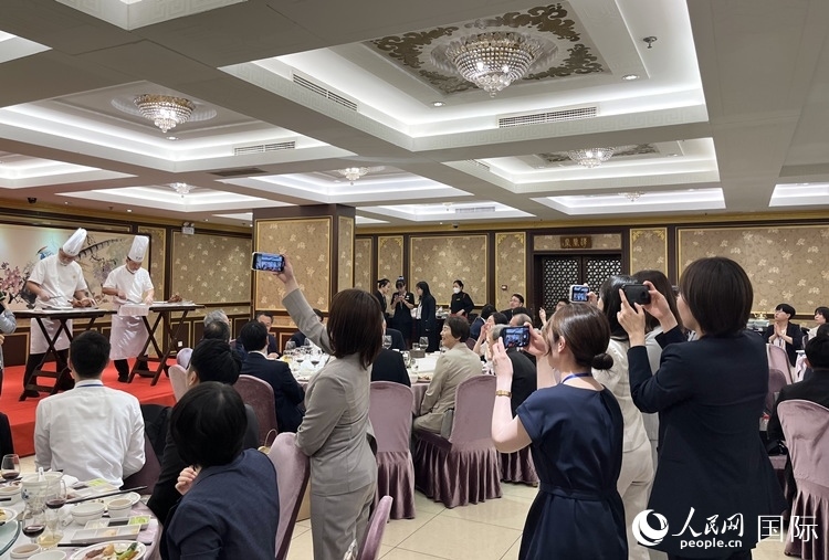 國家級(jí)非物質(zhì)文化遺產(chǎn)、全聚德片鴨工藝吸引代表團(tuán)成員拍照留念。