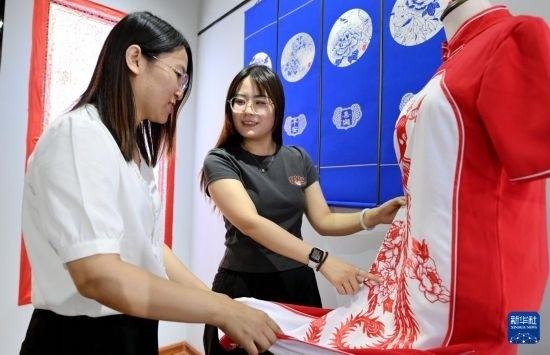 5月31日，在衡水市阜城縣一家剪紙工作室，游客在觀賞帶有剪紙?jiān)氐钠炫邸? width=