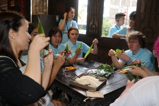 6月9日，美國青年代表在重慶永川松溉古鎮(zhèn)體驗(yàn)包粽子。新華社記者 周思宇 攝