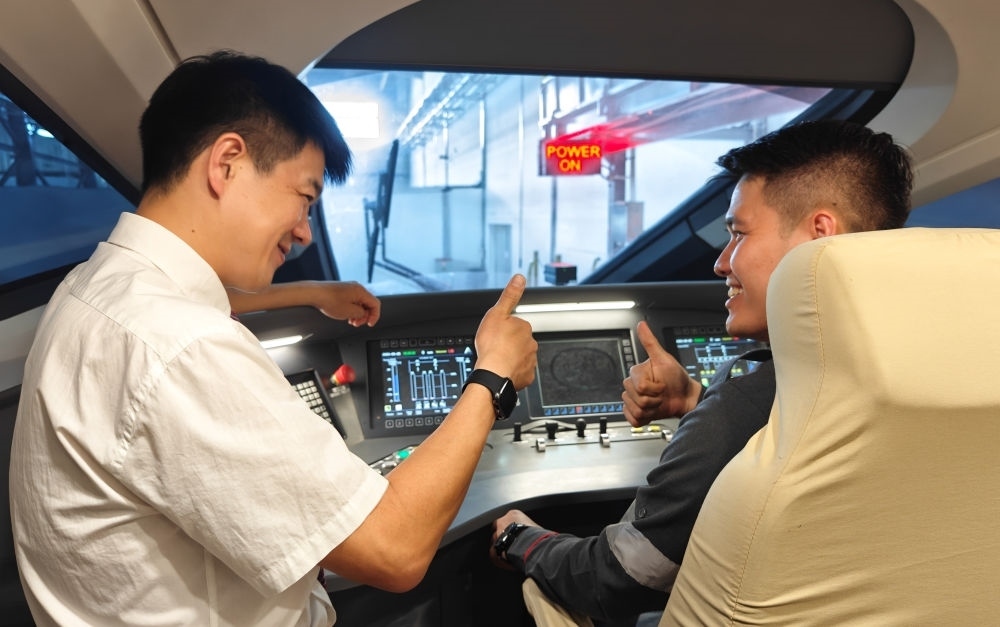 2023年8月25日，在印度尼西亞萬隆的雅萬高鐵德卡魯爾動車所內(nèi)，中國師傅穆振（左）向印尼火車司機(jī)塞蒂亞萬講解動車組出庫前的上電作業(yè)。新華社記者 徐欽 攝