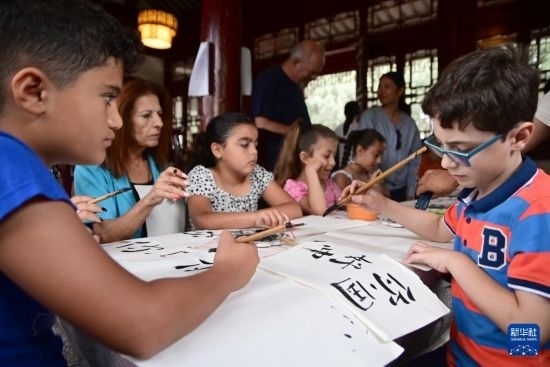 7月4日，在馬耳他桑塔露琪亞市的中國古典園林“靜園”，人們體驗(yàn)中國書法。新華社發(fā)（喬納森·博格 攝）