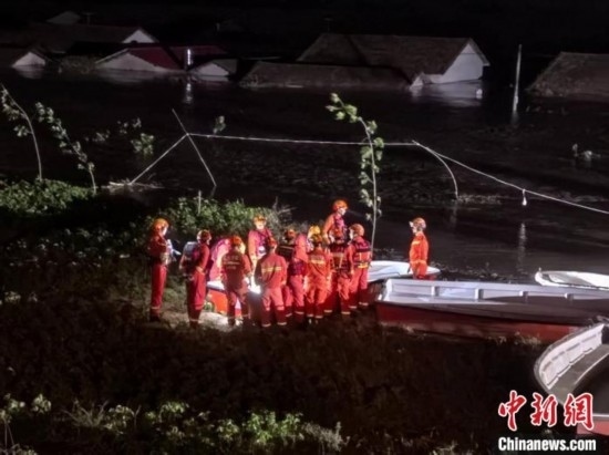  7月6日凌晨3時，在湖南岳陽華容縣團(tuán)洲垸洞庭湖一線堤防，救援人員剛剛完成一次救援任務(wù)，遠(yuǎn)處是被淹的民房。中新社記者 白祖偕 攝