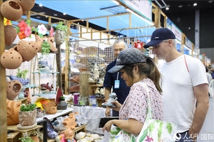 游客在蘭納博覽會特色展位上選購工藝品。人民網(wǎng)記者楊一攝